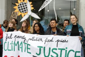 Young climate activists holding a banner that reads Climate Justice = Social Justice