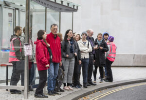 A group of people waiting at a bus stop.
