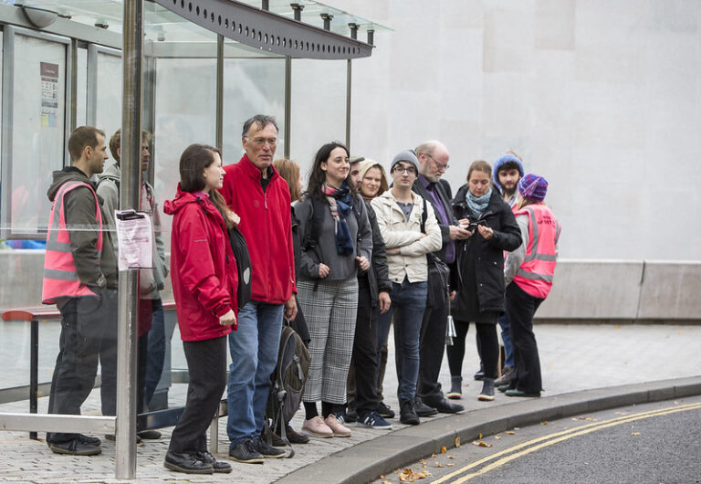 A group of people waiting at a bus stop.