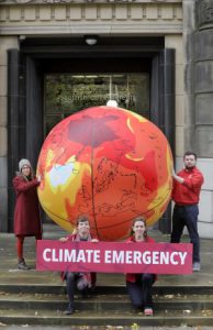 Activists outside St Andrews House with a globe depicting rising temperatures.