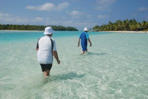 Two people wading through Aitutaki Lagoon