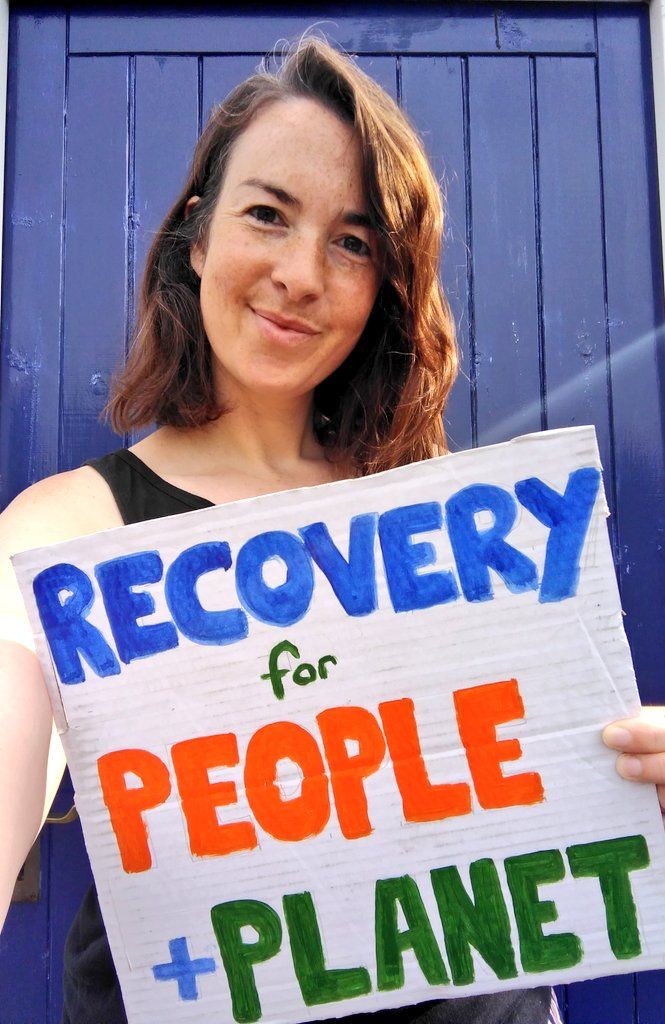 Woman holds painted sign saying 'Recovery for People and Planet'