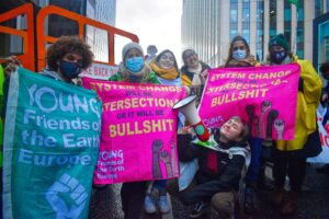 A group of young people holding pink flags that read system change will be intersectional or it will be bullshit