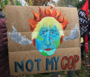a cardboard sign painted with Boris Johnston as an earth on fire with the caption not my cop