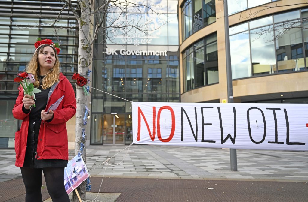 woman stands in front of 'no new oil' banner