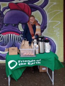woman standing behind 'Friends of the Earth' table