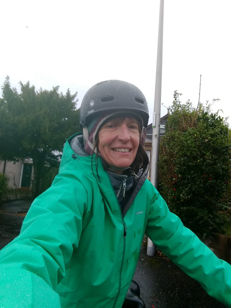Alison Powell from Elephant Refills on her bike with a rain jacket and helmet on.
