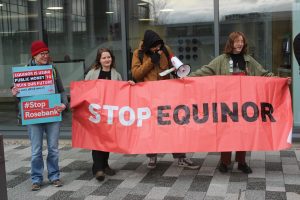 group of 4 people holding stop equinor banner