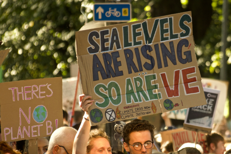 woman holding a placard reading: sea levels are rising, so are we'