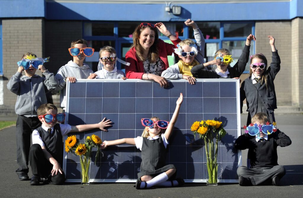 School children around a solar panel