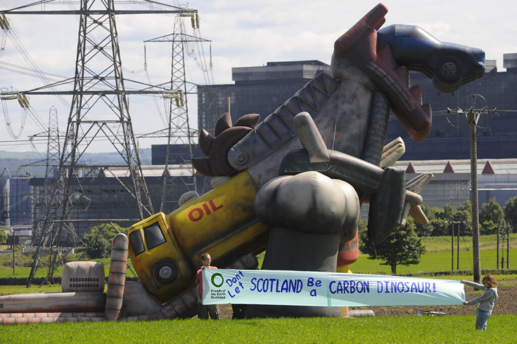 Giant dinosaur inflatable in a field in front of a power station