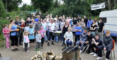 A mixed group of people in front of a gate by a forest