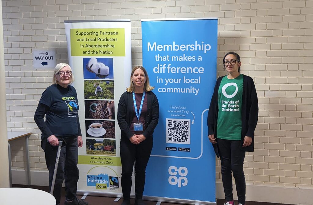 three women standing in front of two pop up banner