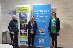 three women standing in front of two pop up banner