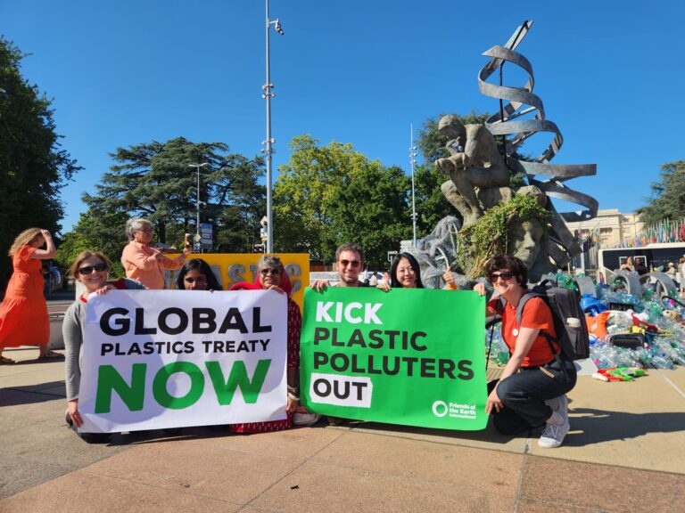 A group of people holding signs that state 'global plastics treaty now' and 'kick plastic polluters out'