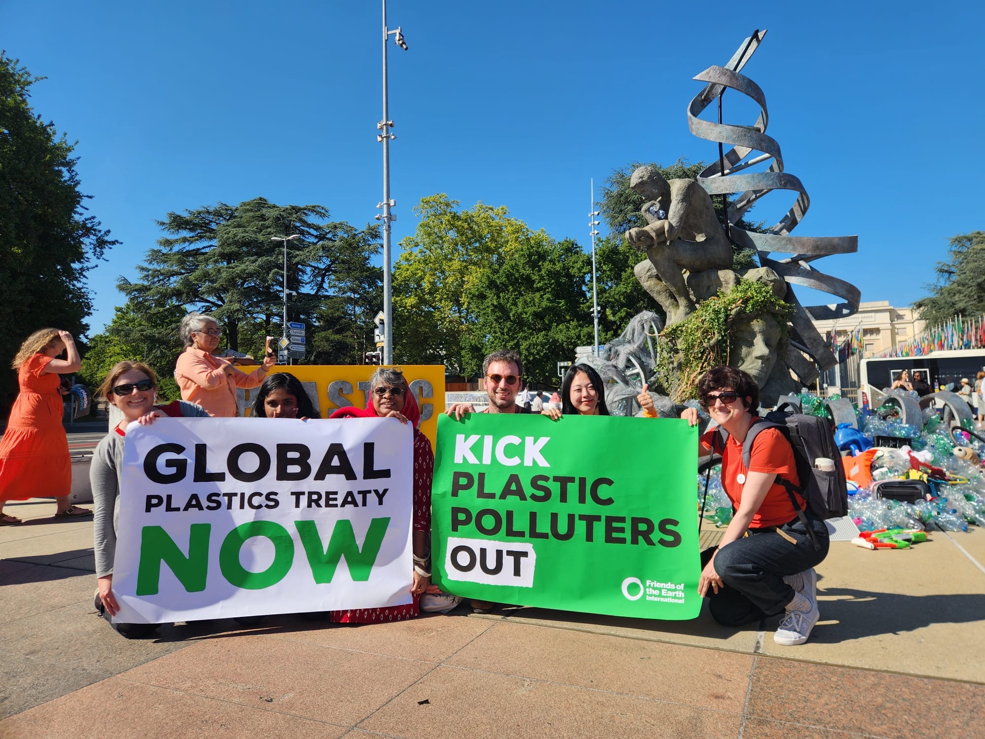 A group of people holding signs that state 'global plastics treaty now' and 'kick plastic polluters out'