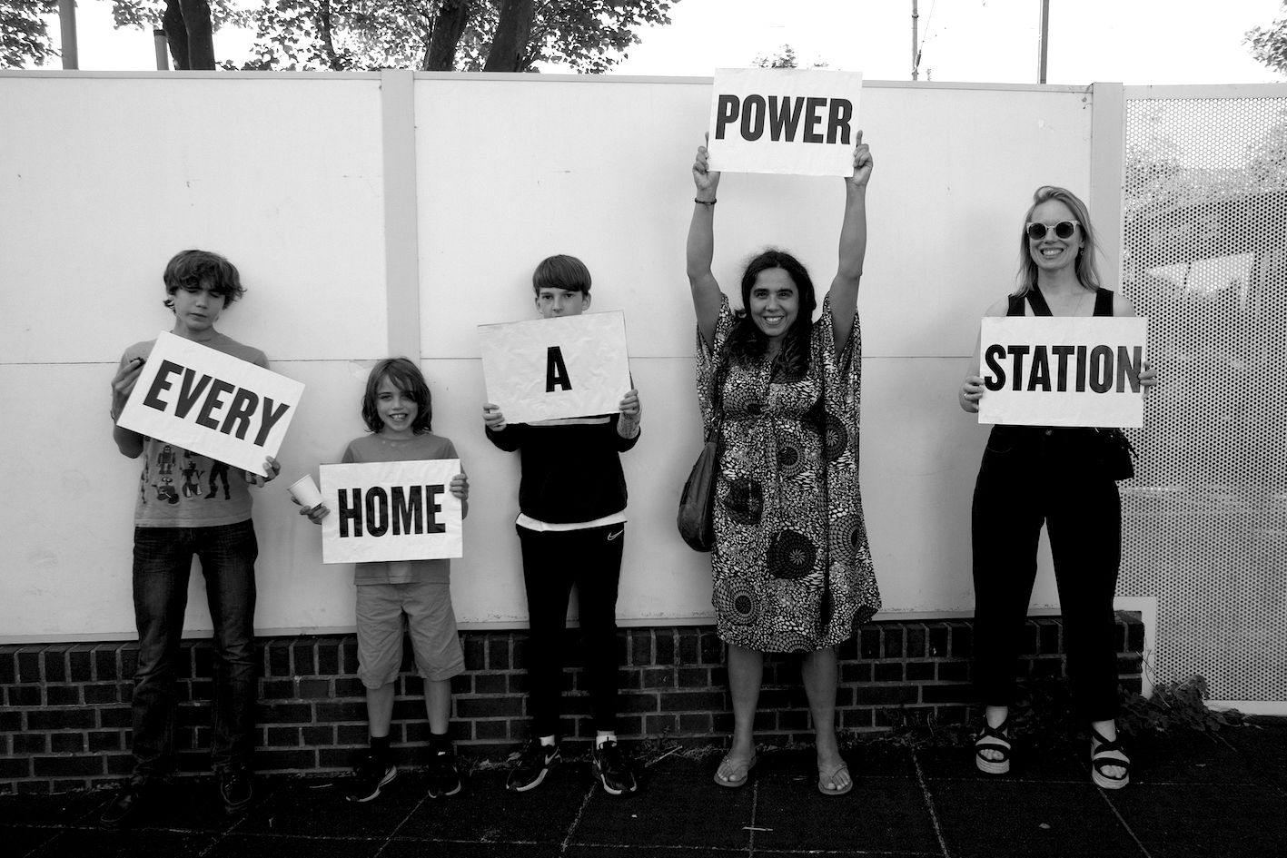 five people holding signs reading "every home a power station"