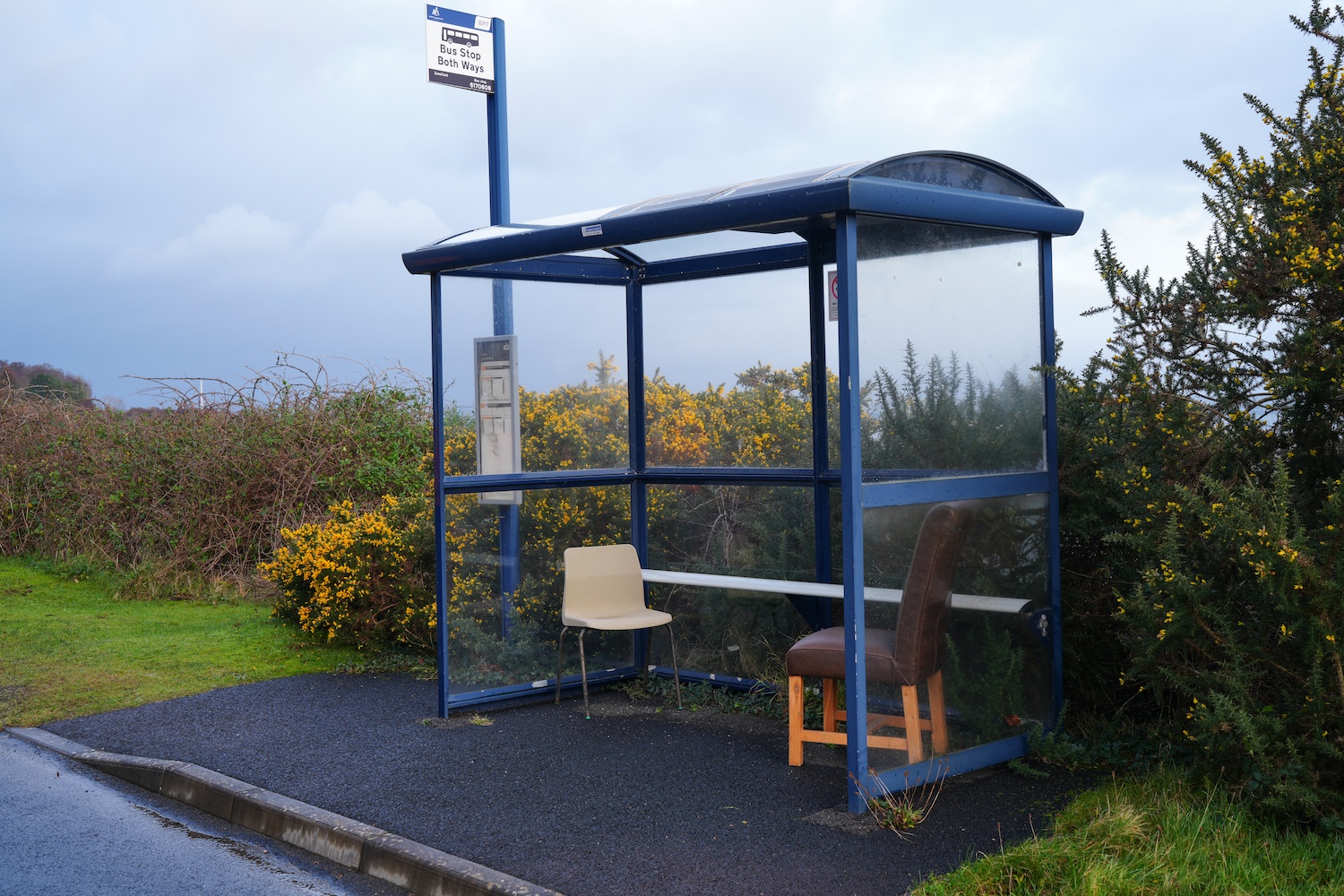 empty isolated blue bus shelter with two chairs