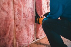 man installing pink wall insulation