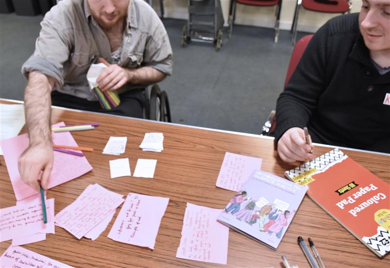 two people with lots of cards with writing on a table