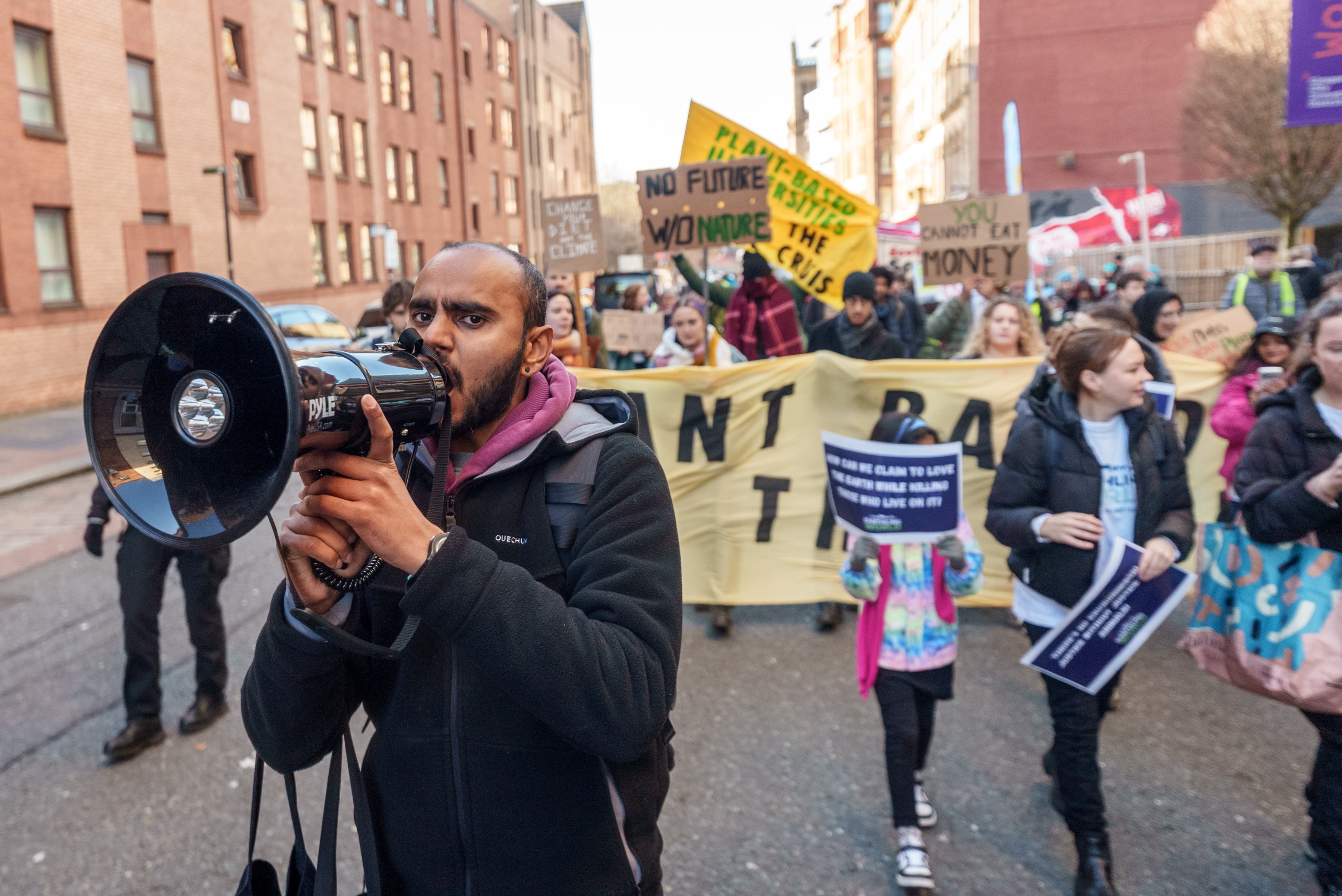 man talking into a megaphone walking in climate march