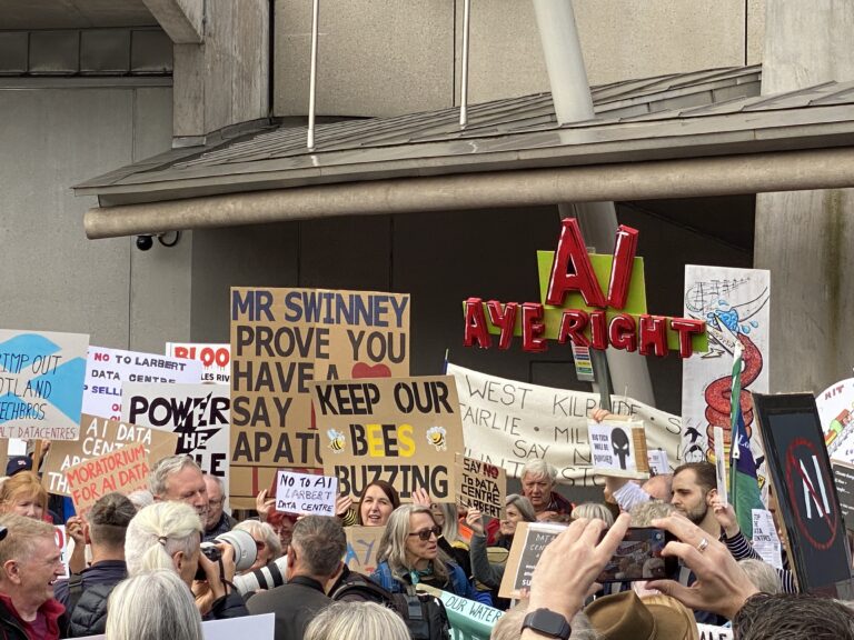 Large crowd of anti AI data centre protestors outside the Scottish Parliament with signs and placards