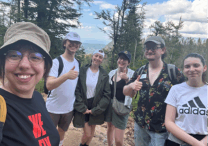 six young people in a selfie with a mountain backdrop
